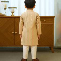 Child wearing a traditional outfit standing in front of a wooden cabinet.