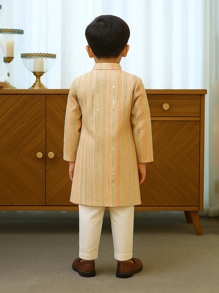 Child wearing a traditional outfit standing in front of a wooden cabinet.