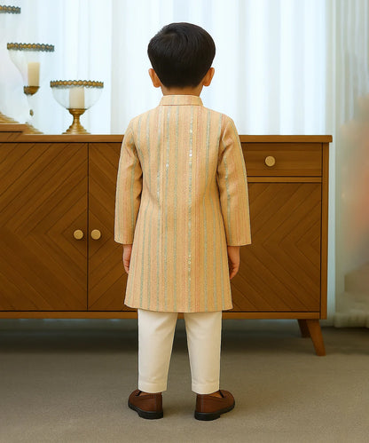 Child wearing a traditional outfit standing in front of a wooden cabinet.