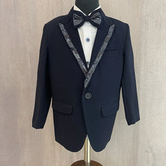 This is a navy coloured coat suit and comes with matching pants, a white shirt and a black bow. It features beautiful sequin detailing on the collar and a bow curated from a black sequin fabric