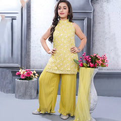 Woman in a yellow traditional outfit standing in front of decorative vases with flowers.