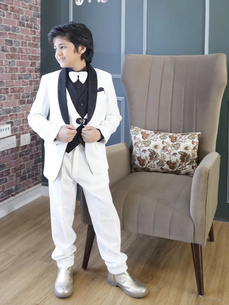 This black and white coloured coat suit for boys consists of a coat, matching pants, a dual-style waistcoat, and a self-textured shirt. It features a matching bow, a cute broach, a pocket square and shimmer detailing on the collar that adds grace to the look.