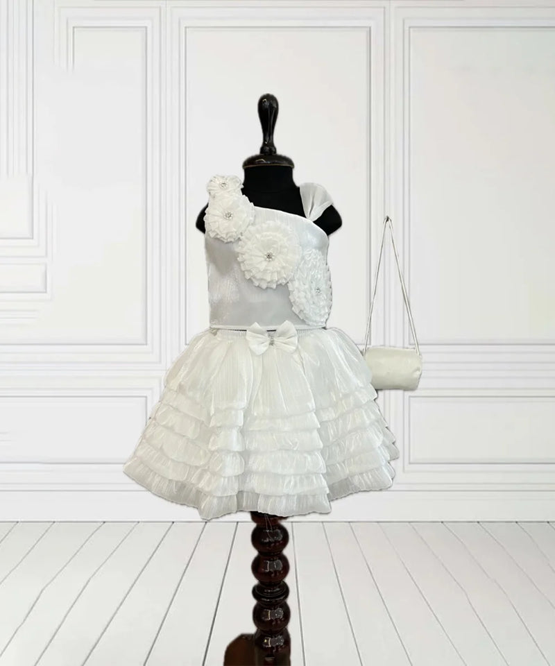 This White Coloured kids birthday wear dress consists of a crop top, a skirt and a matching handbag. It features floral detailing on the top and a cute bow on the waist.