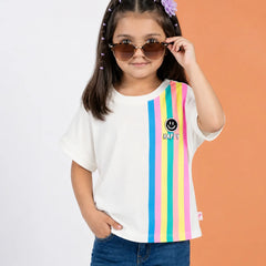 A young girl with sunglasses and a purple flower hair clip wears a white t-shirt with vertical rainbow stripes on the right side and a smiley face logo with 'KAPY' text. She is paired with blue jeans, standing against a split white and orange background.